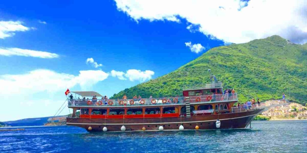 
 A boat tour offers a unique perspective on the stunning landscape, with towering mountains plunging into the crystal-clear waters of the bay. 